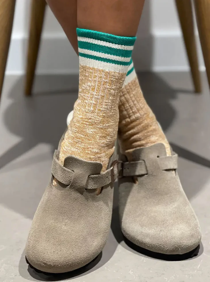 Woman wearing green and tan socks with clogs