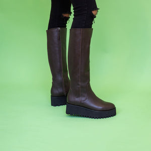 Brown knee high boots worn with black jeans